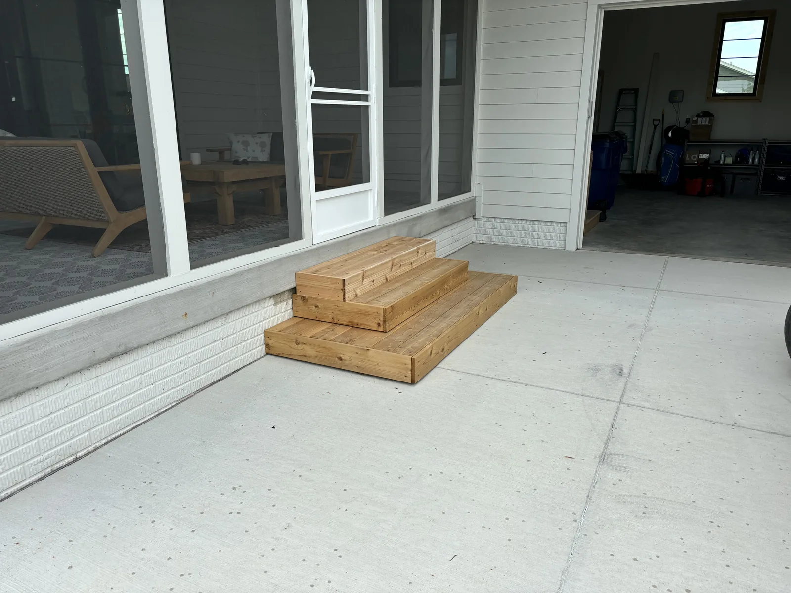Broom-finished concrete patio with a custom cedar step unit leading up to a screened porch door
