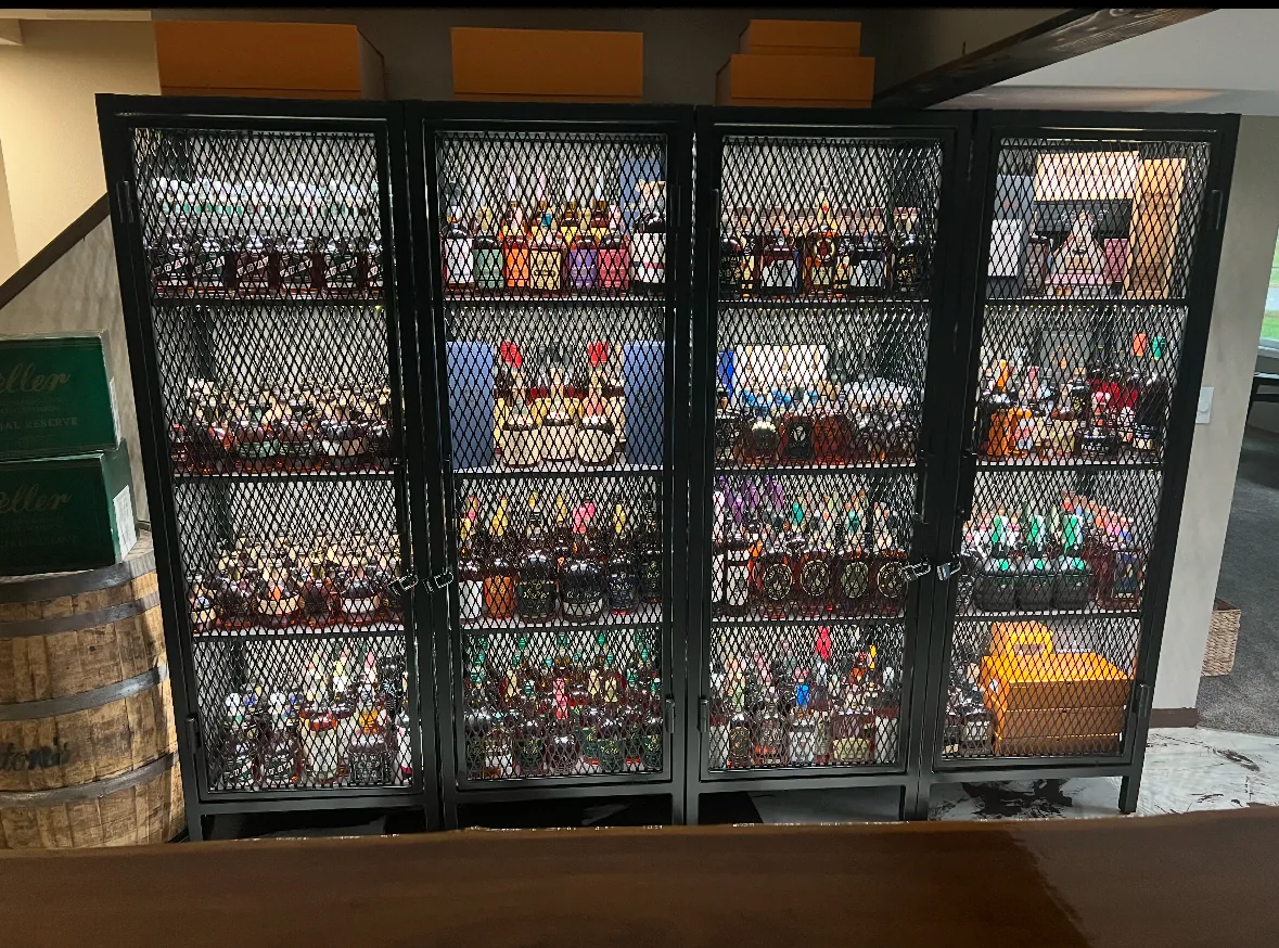 Custom black metal mesh display cabinets built into a basement bar area for a bottle collection