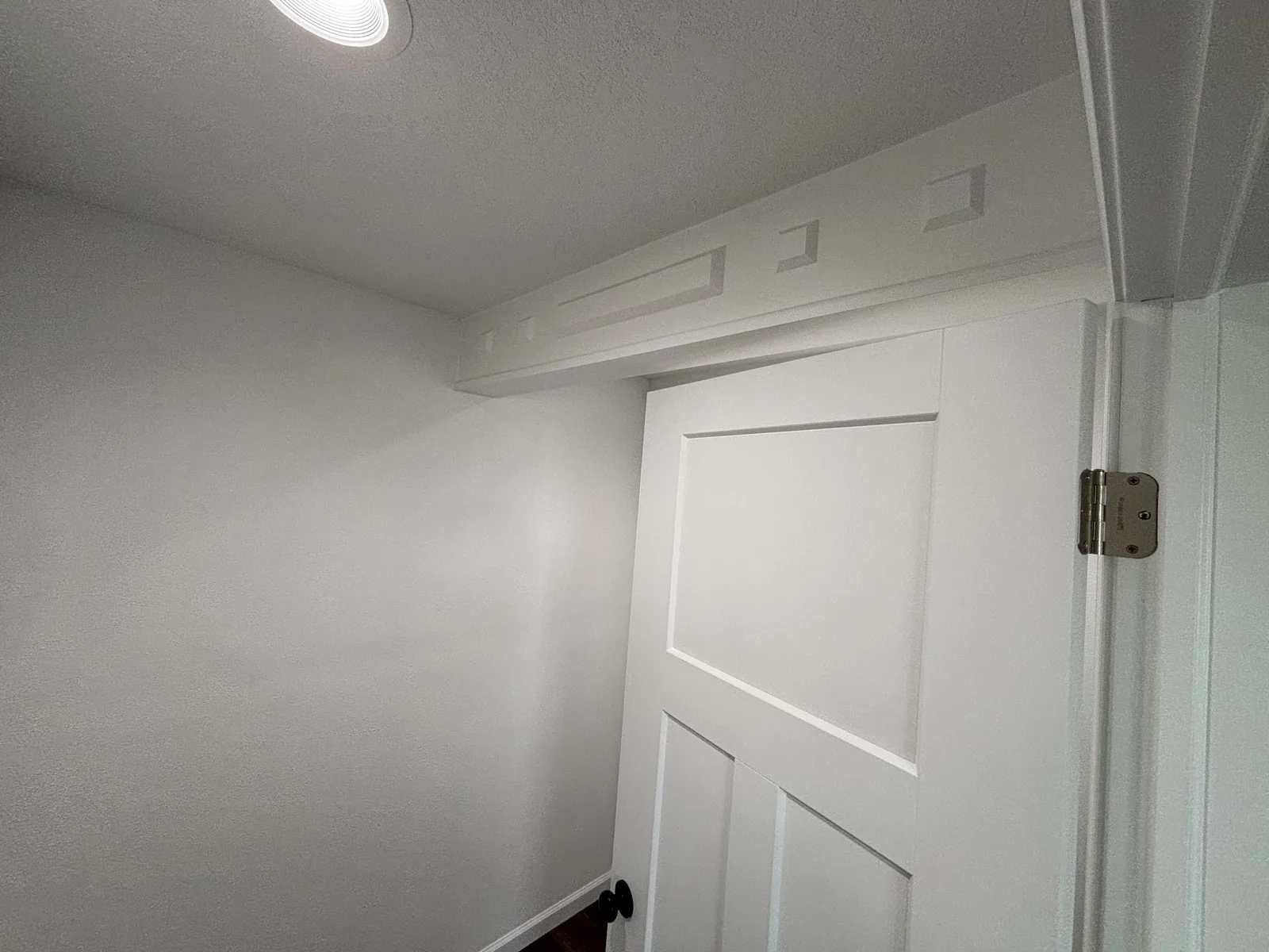 Finished interior door with painted trim, transom detail above, and fresh paint on textured walls