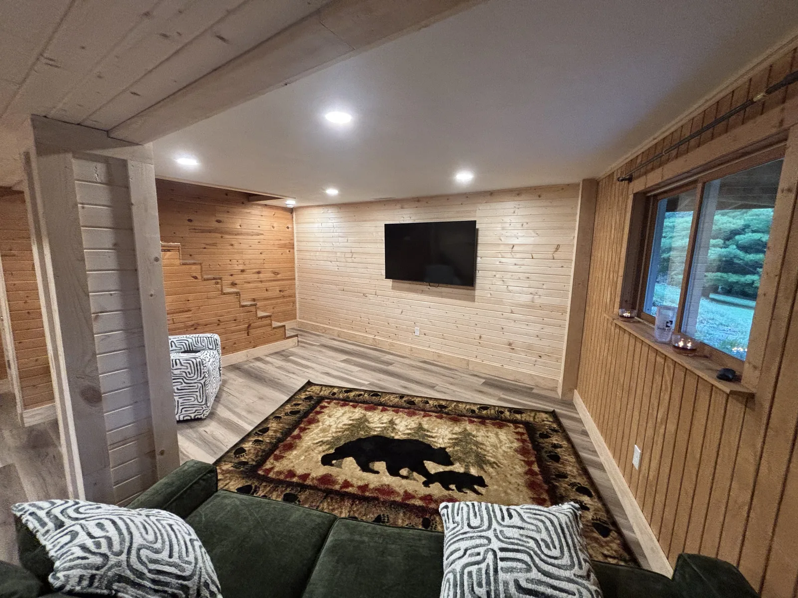 Finished lower level with knotty pine plank walls, recessed lighting, and wood-look plank flooring