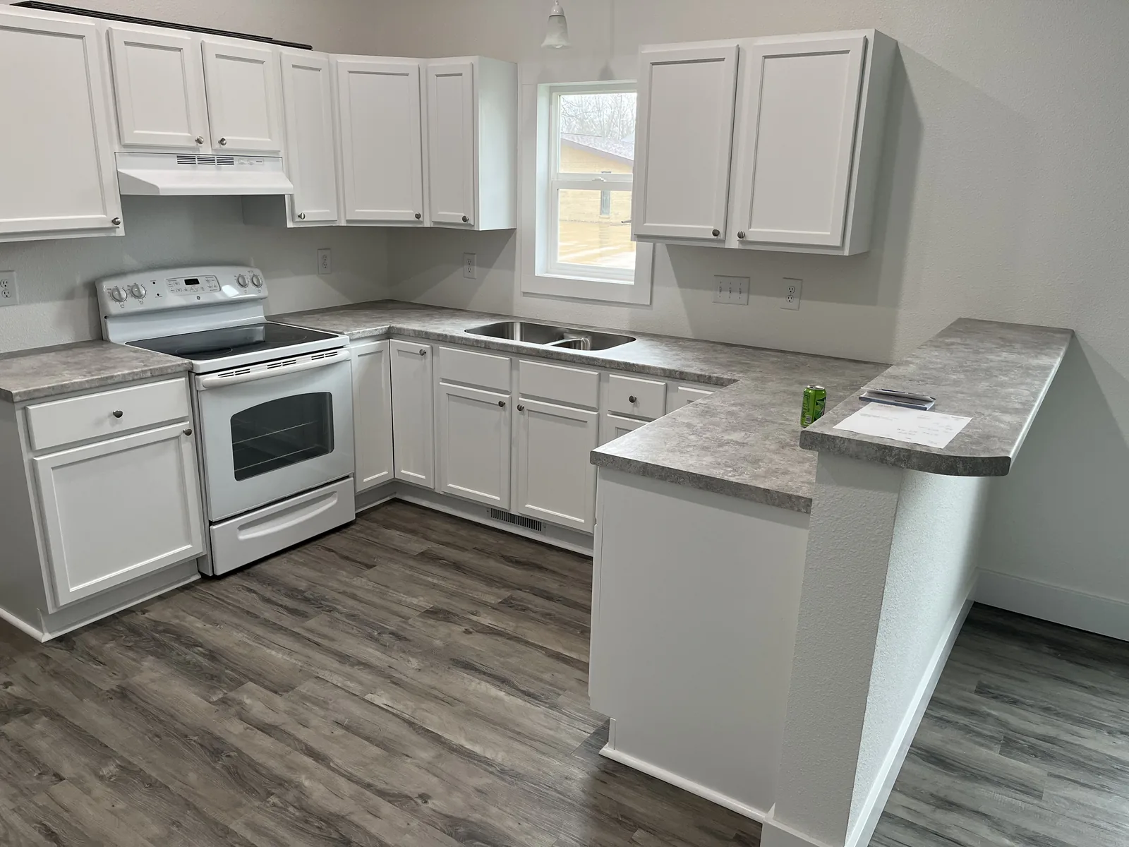 Finished kitchen with white cabinets, gray laminate countertops, and wood-look vinyl plank flooring