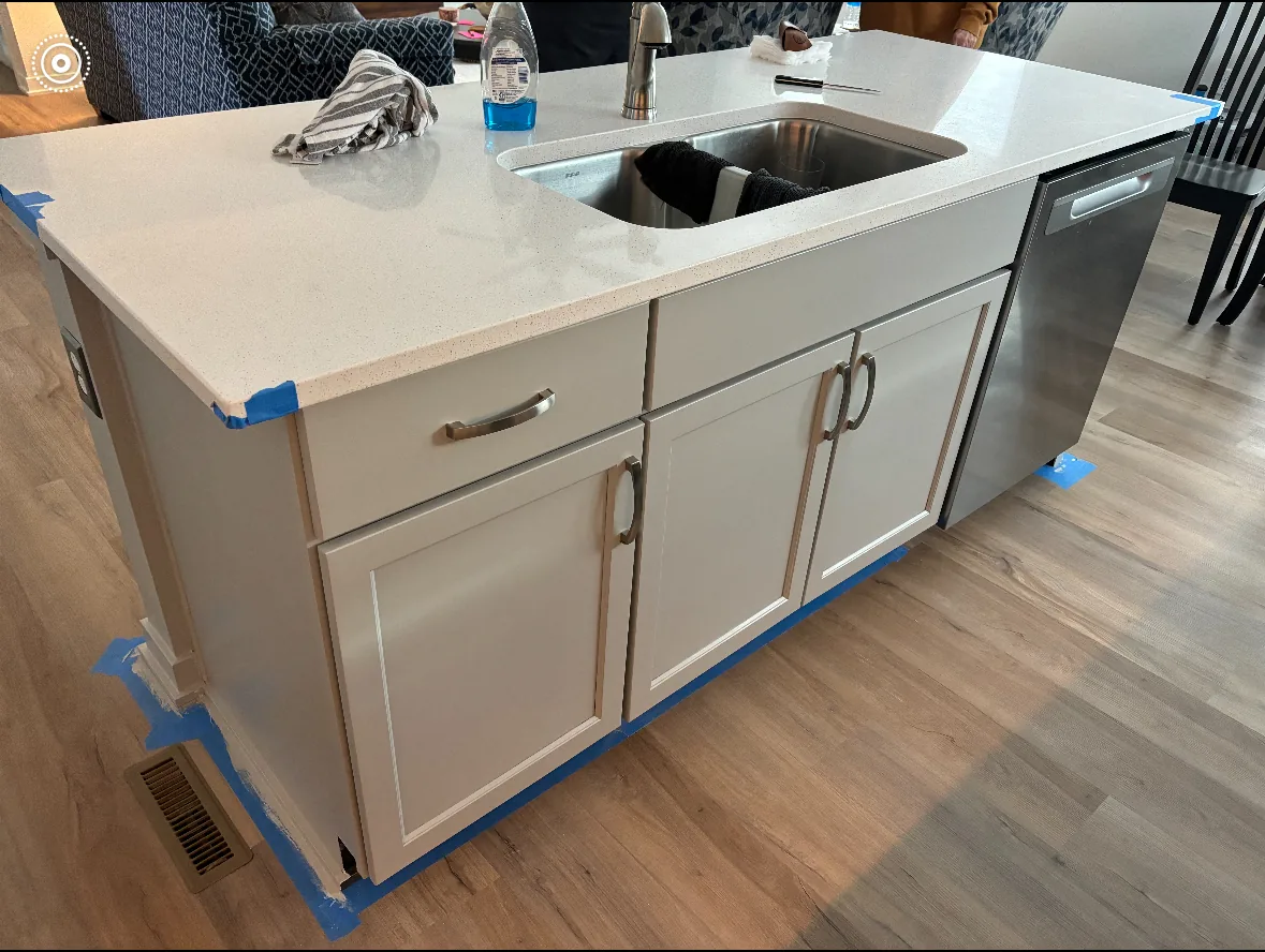 Refinished kitchen island with painted cabinet fronts, quartz countertop, and undermount sink during a cabinet refinishing project