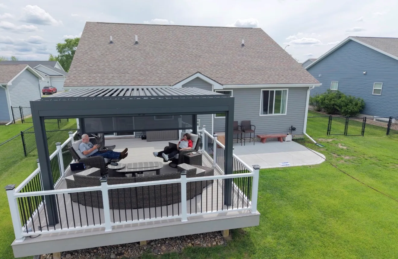 Aerial view of a composite deck with white railing and black balusters shaded by a modern louvered pergola over a lounge area