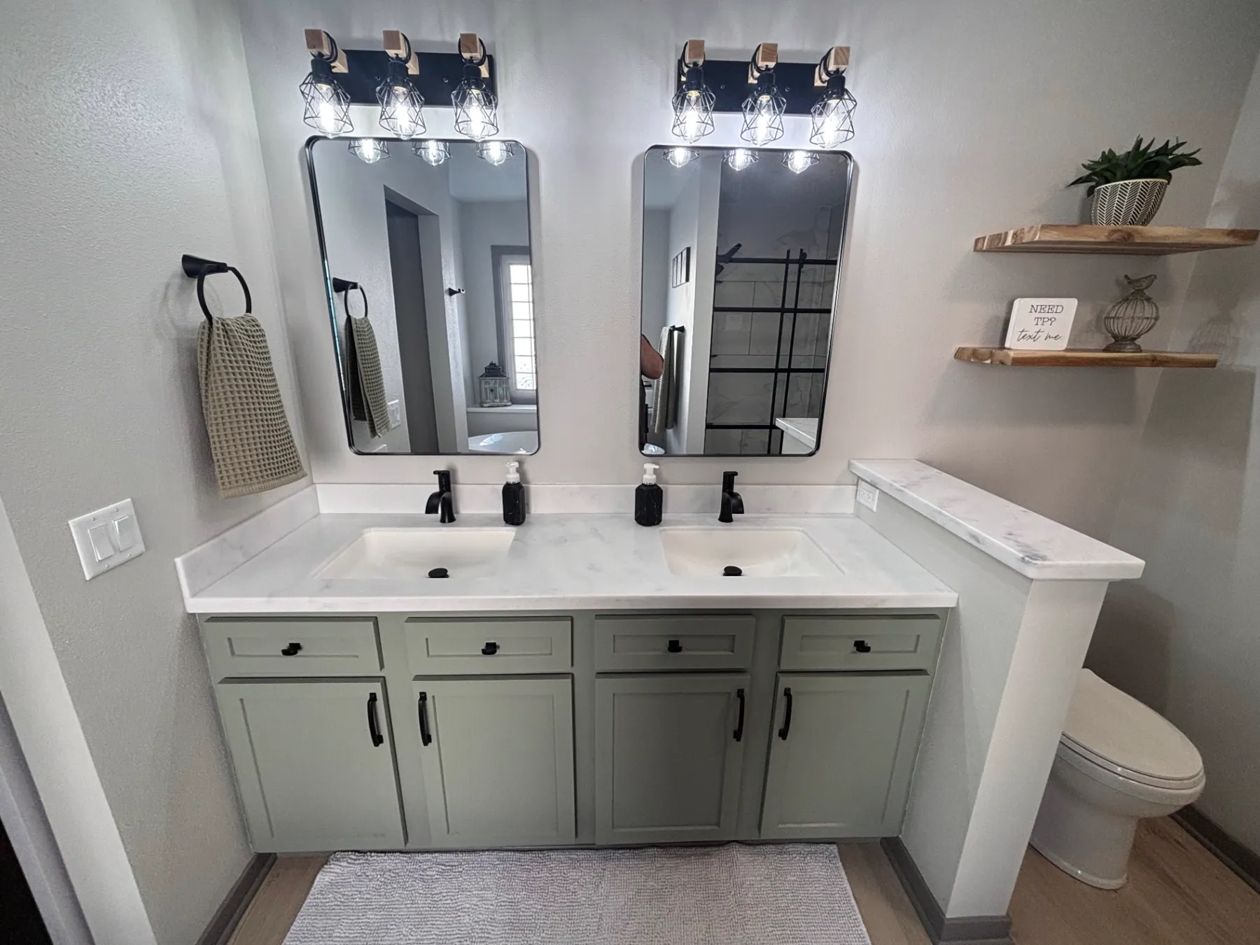 Double vanity with sage green shaker cabinets, marble-look quartz countertop, black faucets, and framed black mirrors