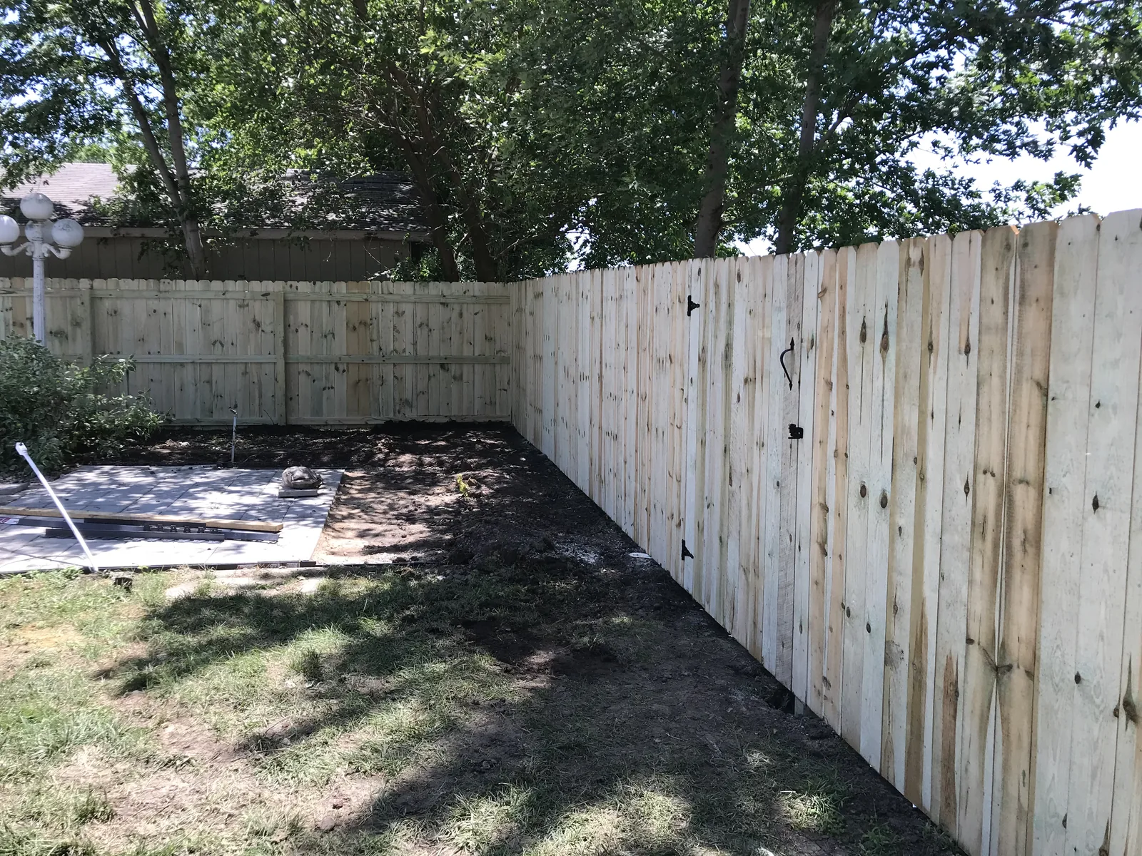 Backyard privacy fence with a gated section and fresh soil line along the base