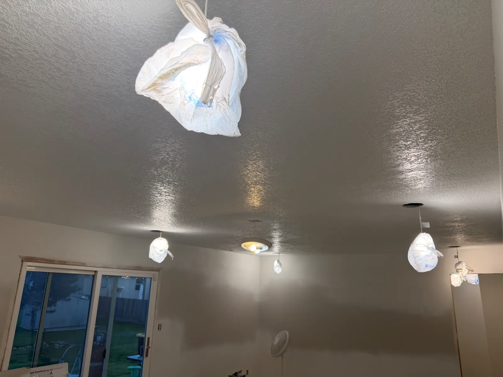 Newly textured and painted living room ceiling with light fixtures masked off during finishing work