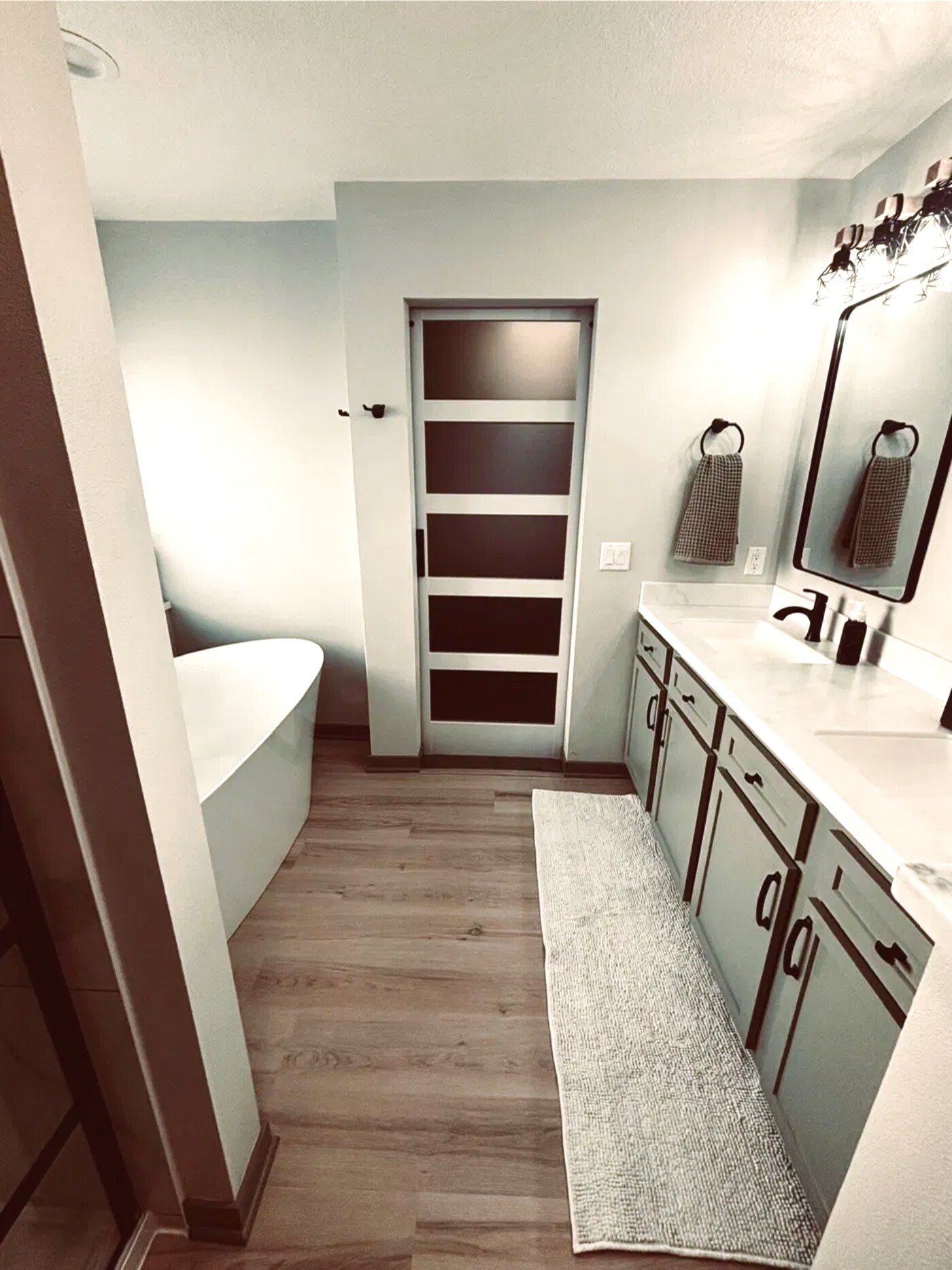 Remodeled bathroom with freestanding soaking tub, sliding barn door, and long vanity