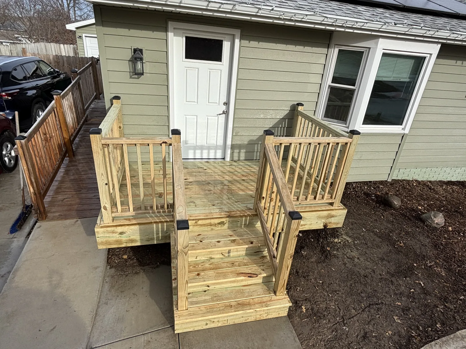 New pressure-treated deck landing and steps with railing at a side entry door